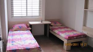 Two sharing room at Swarnaa Ladies Hostel with two single beds and a study table
